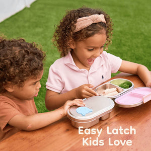 Two children with easy-open stainless steel snack boxes on a wooden table outdoors.